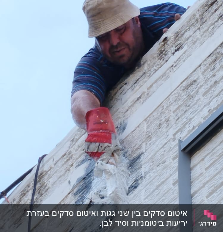 אדם מורח חומר איטום על קיר חיצוני